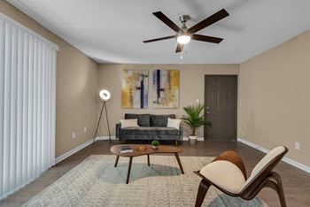 Living room with ceiling fan and private patio access.